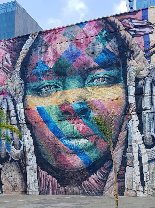 Żywy, wielobarwny mural afrykańskiej kobiety z geometrycznymi wzorami.