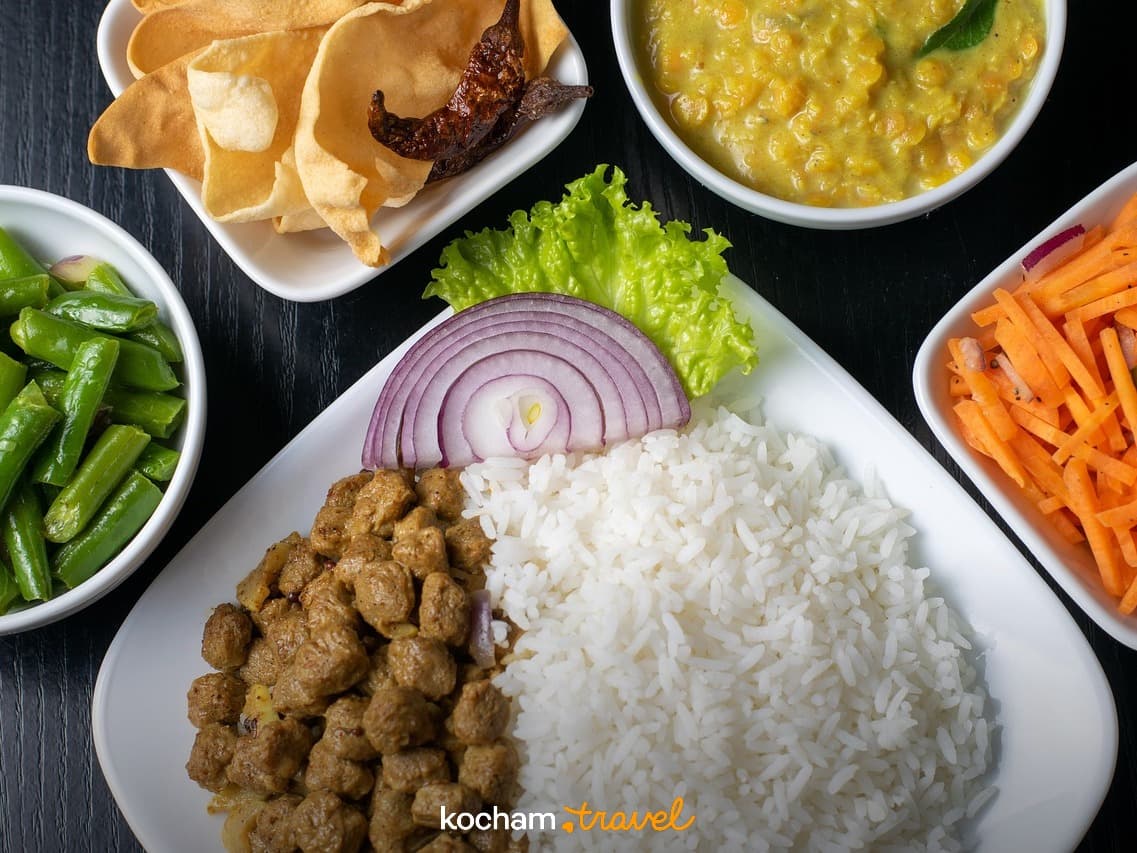 Kolorowe dania kuchni azjatyckiej: ryż, curry, warzywa, dal, papadamy.