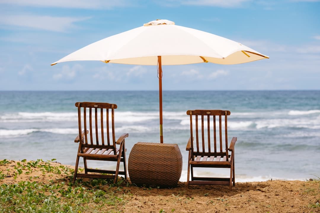 Leżaki drewniane, stolik, parasol na piaszczystej plaży oceanicznej.
