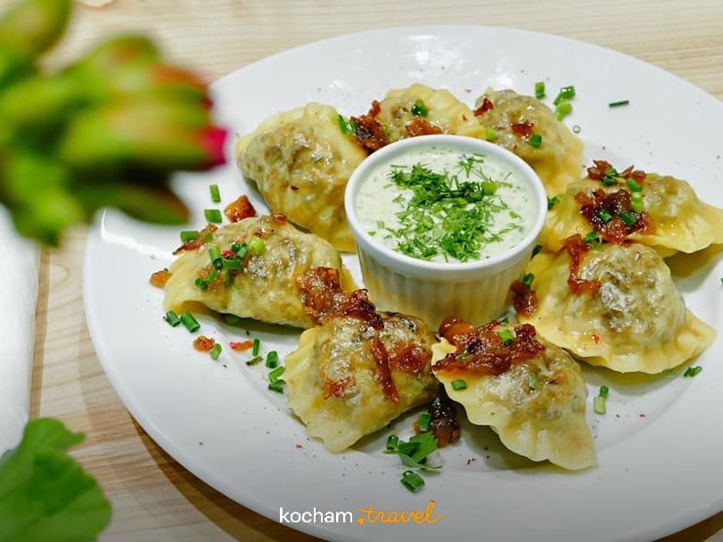 Apetyczne pierogi z sosem, chrupiącą cebulką i zielonym szczypiorkiem.