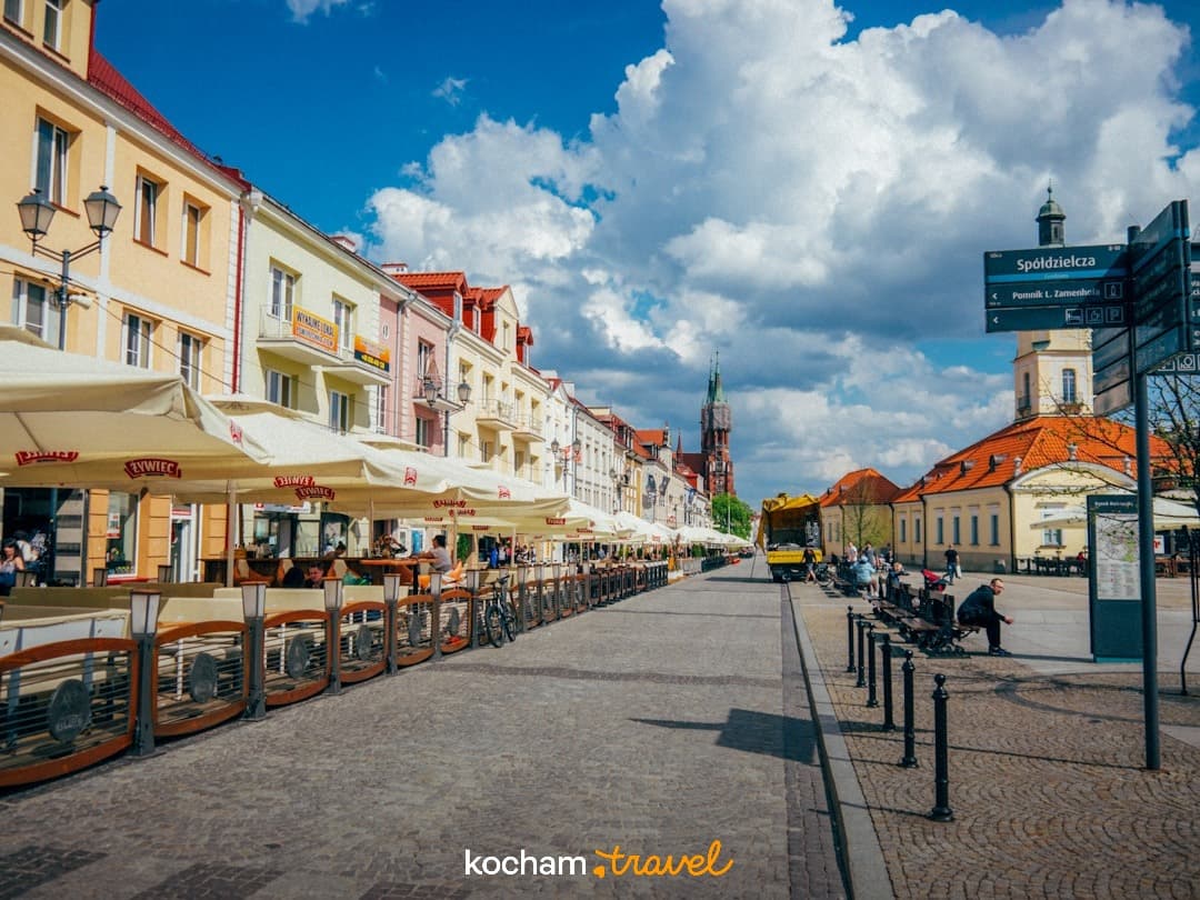 Słoneczna ulica w Białymstoku, kolorowe kamienice, kawiarnie, ludzie.