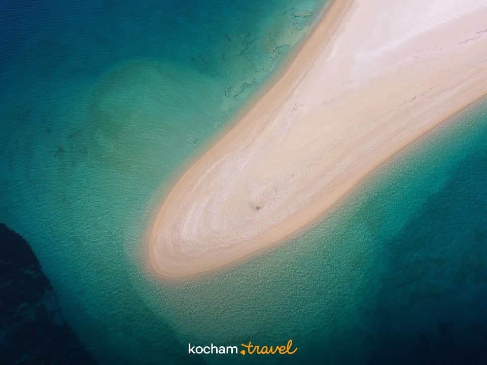 Rajska piaszczysta mierzeja otoczona turkusową wodą oceanu.