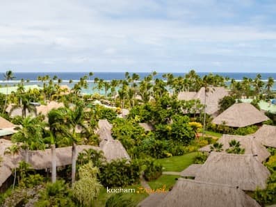 Panoramiczny widok tropikalnego kurortu z bungalowami i palmami nad oceanem.