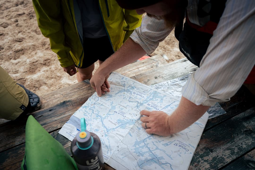 Ludzie studiujący mapę szlaków na rustykalnym drewnianym stole.
