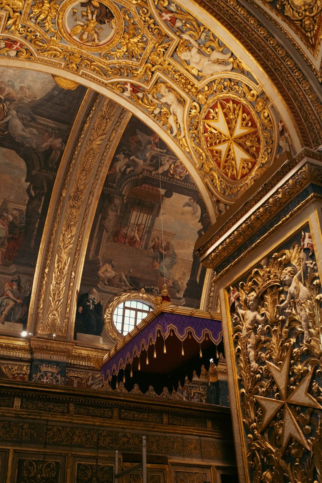 Wspaniałe, złocone wnętrze katedry z freskami, krzyżem maltańskim i baldachimem.