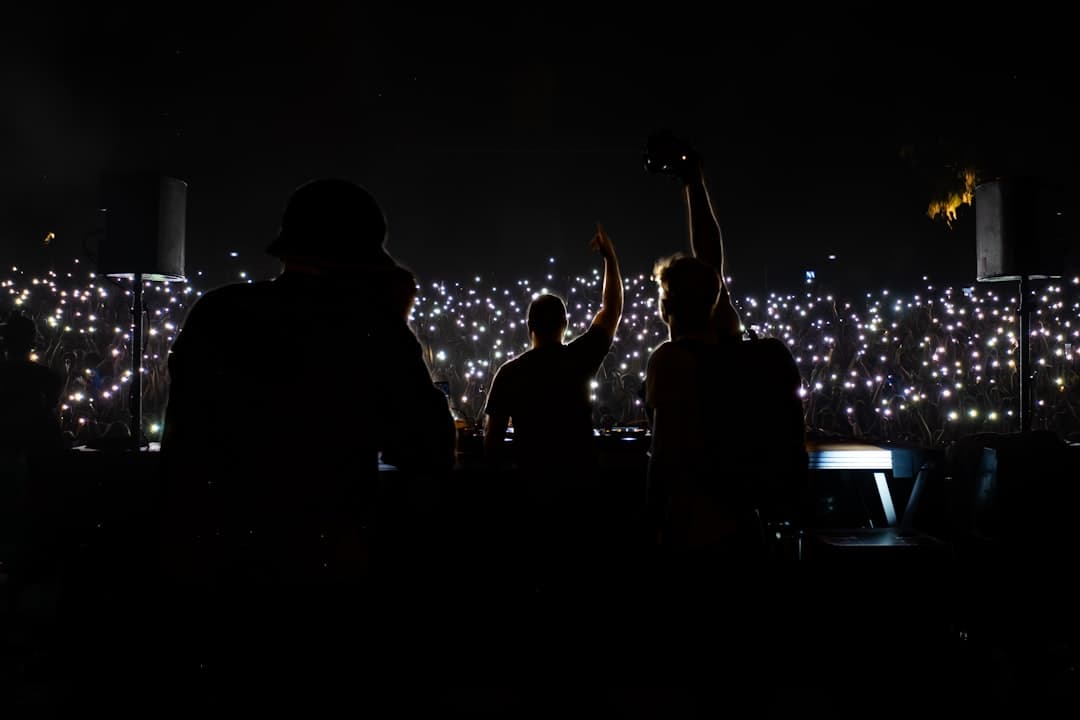 Sylwetki DJ-ów na scenie przed rozświetlonym tłumem na koncercie.