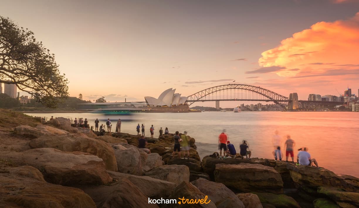 Fotografowie uwieczniający zachód słońca nad Operą i Mostem w Sydney.
