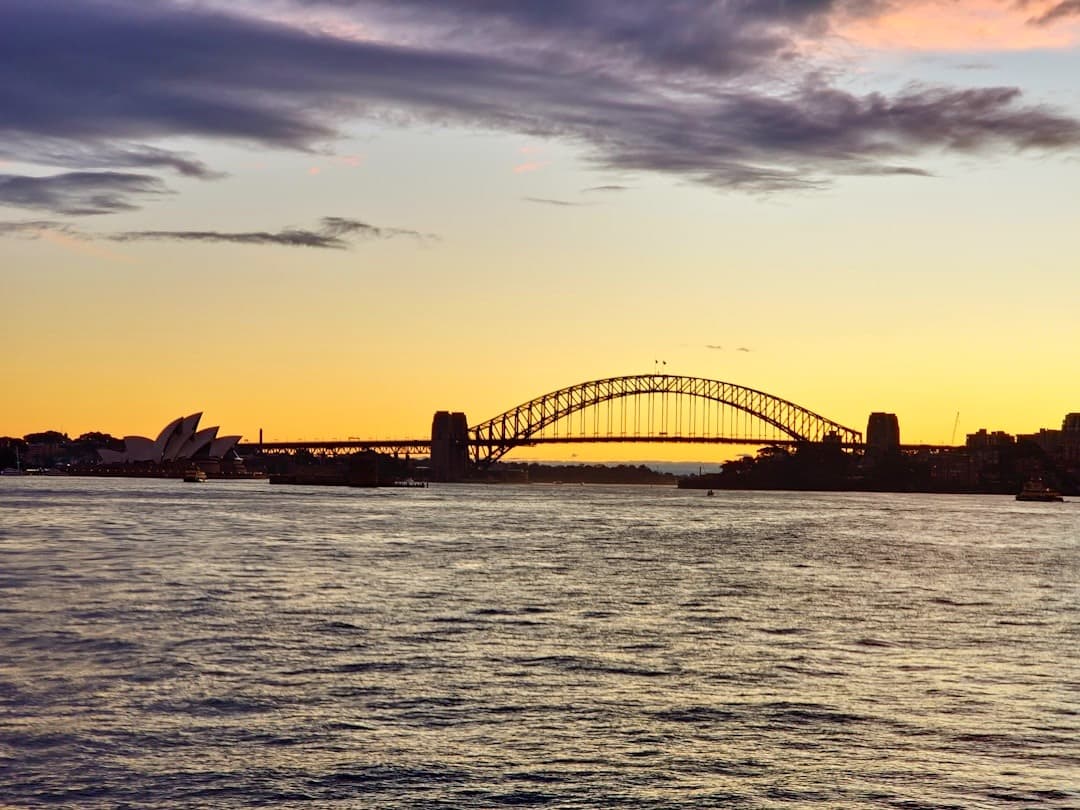 Ikoniczny widok Sydney: Opera i Most Harbour Bridge o zachodzie słońca.