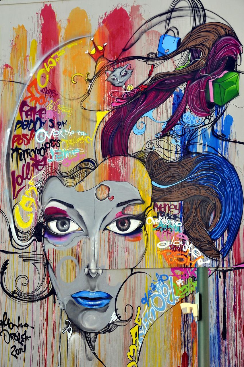 Kolorowy mural graffiti ze stylizowaną twarzą kobiety, kotem i napisami.
