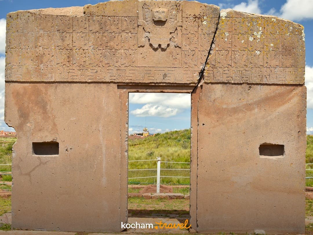Monumentalna starożytna kamienna brama z rzeźbieniami na stanowisku archeologicznym.
