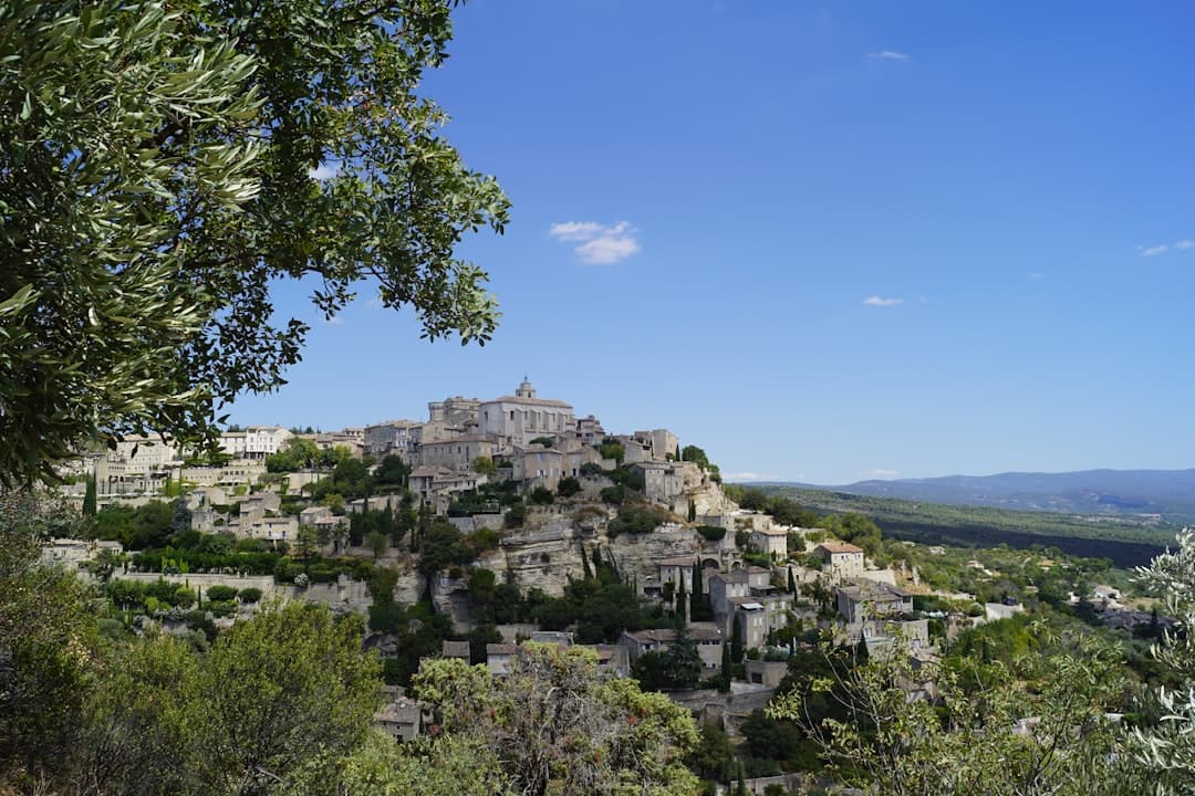 Gordes, Prowansja: kamienna wioska na wzgórzu, drzewa oliwne, błękitne niebo.