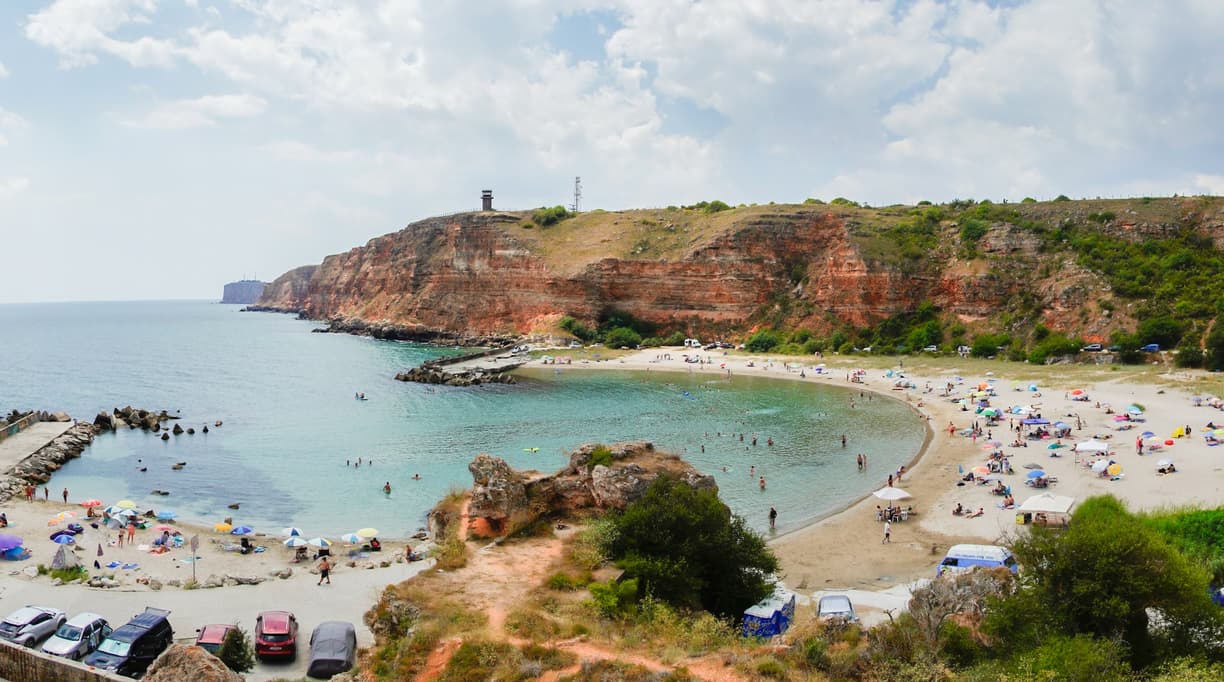 Malownicza plaża w zatoce otoczona czerwonymi klifami i turkusowym morzem.