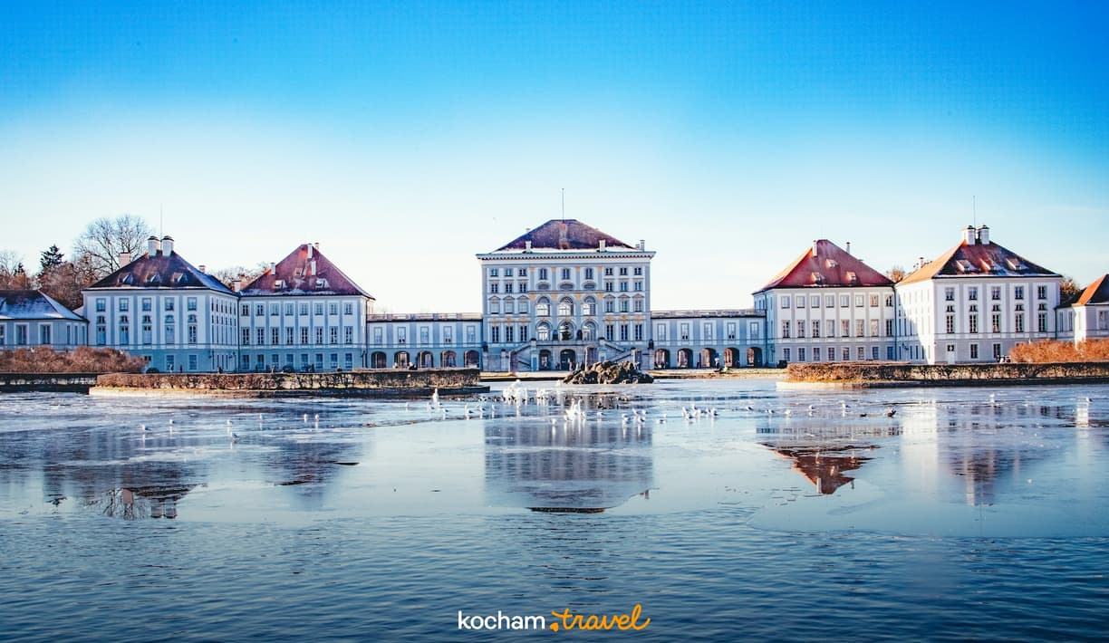 Zimowy Pałac Nymphenburg w Monachium, odbity w zamarzniętym kanale.
