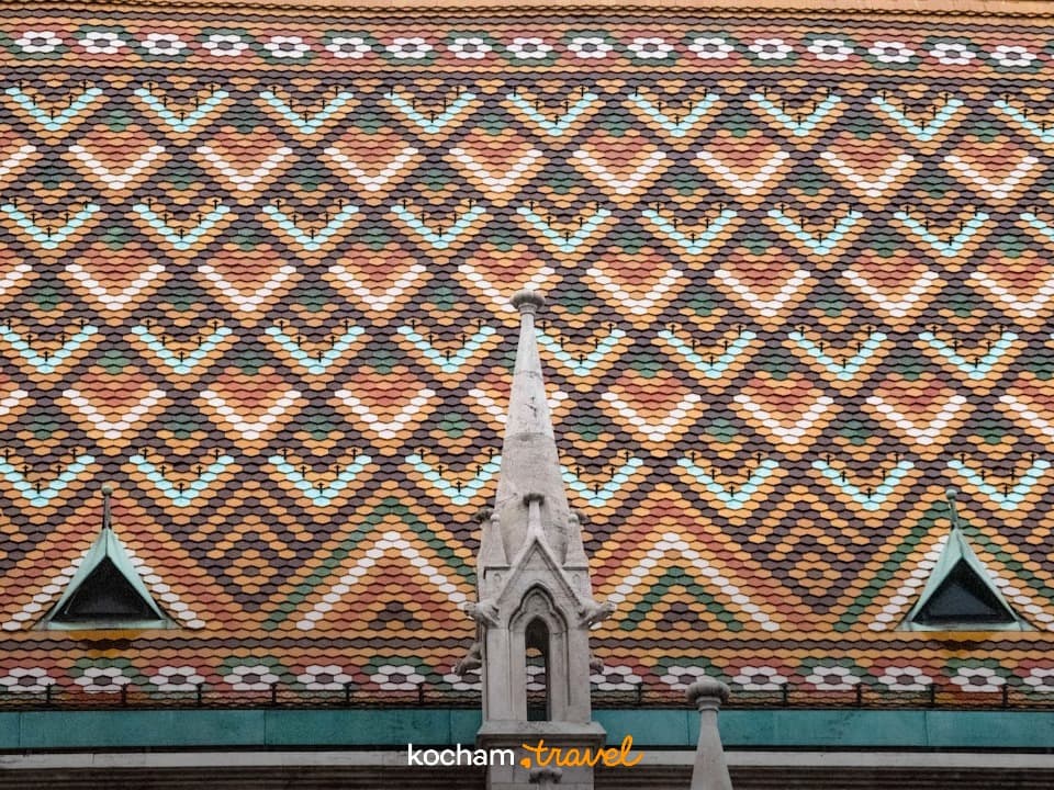 Kolorowy, wzorzysty dach budynku, detale architektoniczne, iglica.