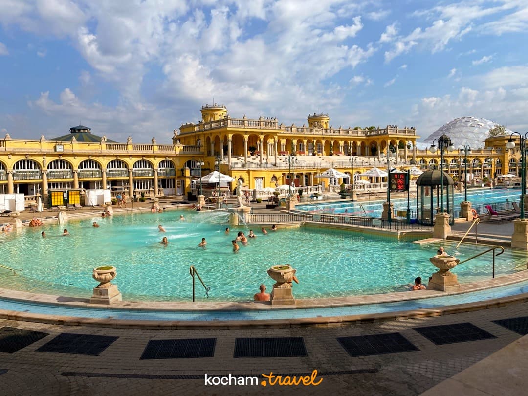 Szechenyi Łaźnie Budapeszt, baseny termalne, żółta architektura, ludzie pływający.