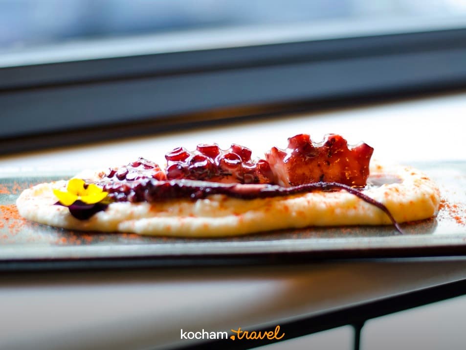 Delikatna ośmiornica na puree, udekorowana kwiatem, danie restauracyjne.