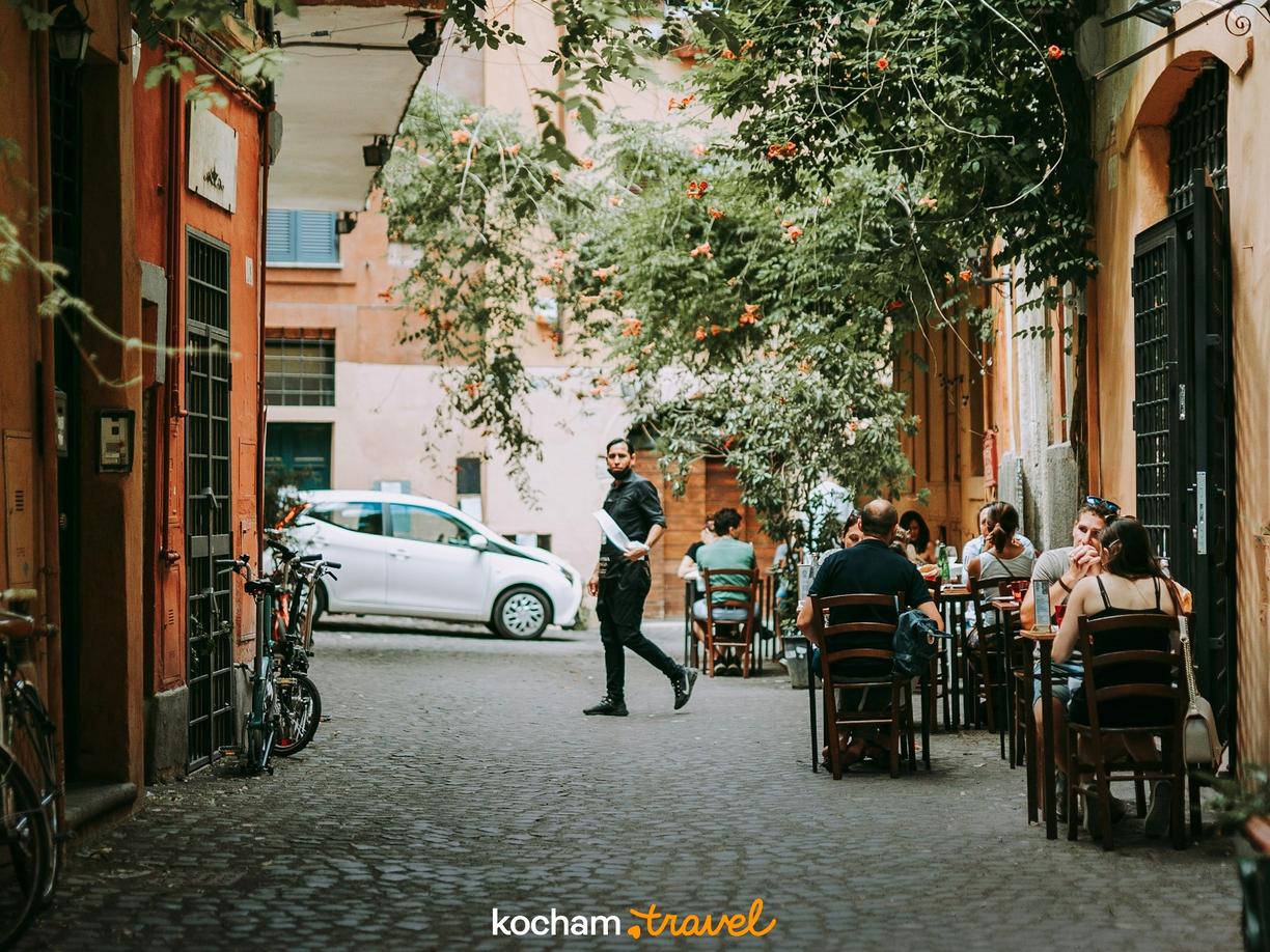 Tętniąca życiem brukowana uliczka z restauracją i kelnerem w śródziemnomorskim mieście.