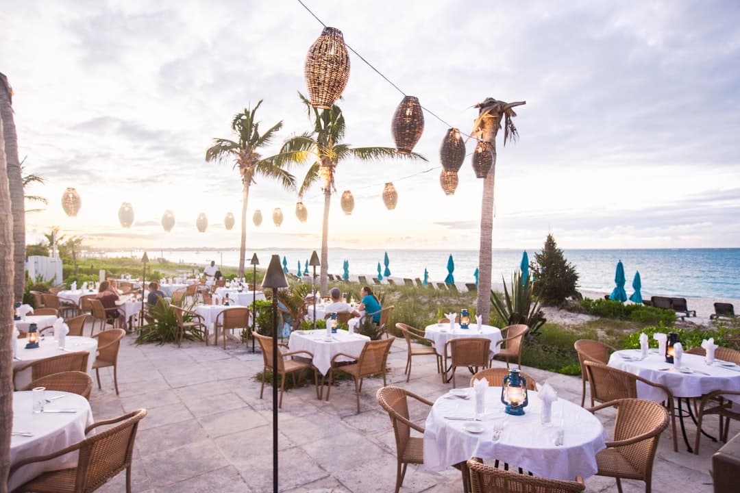 Restauracja na świeżym powietrzu przy plaży z palmami i lampionami.