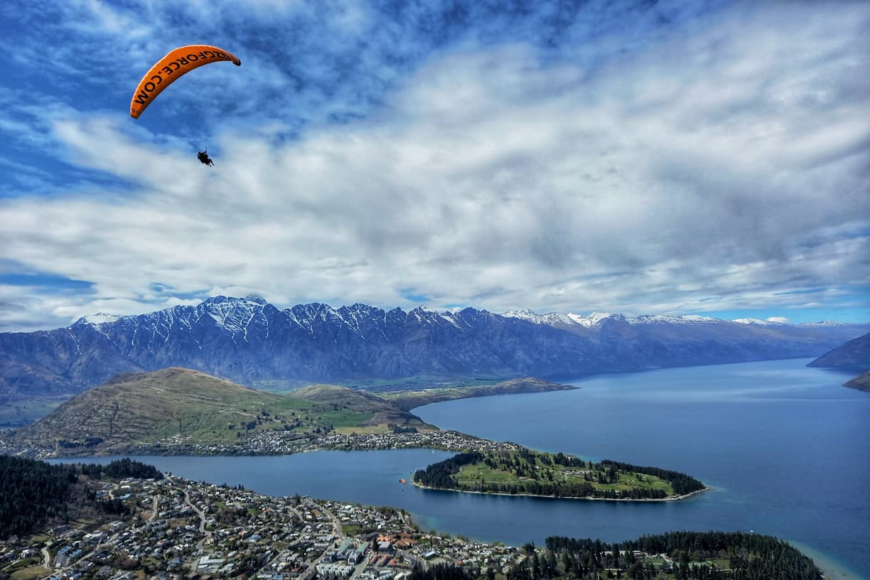 Paralotnia nad Queenstown, jezioro Wakatipu i ośnieżone góry.