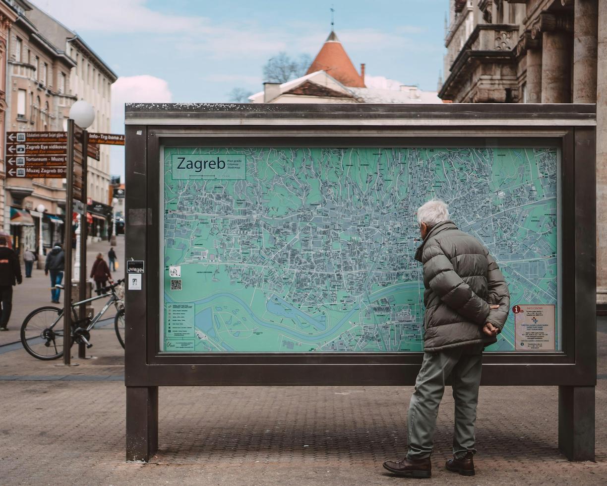 Starszy mężczyzna nawiguje po Zagrzebiu, studiując mapę ulic.