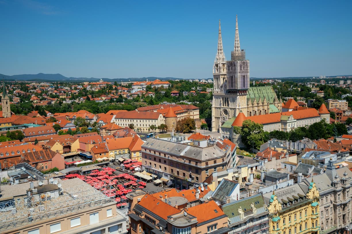 Słoneczna panorama Zagrzebia z katedrą i rynkiem pełnym parasoli.