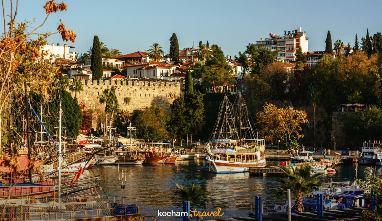 Słoneczny port w Antalyi, Turcja, z tradycyjnymi statkami i zabytkową zabudową.