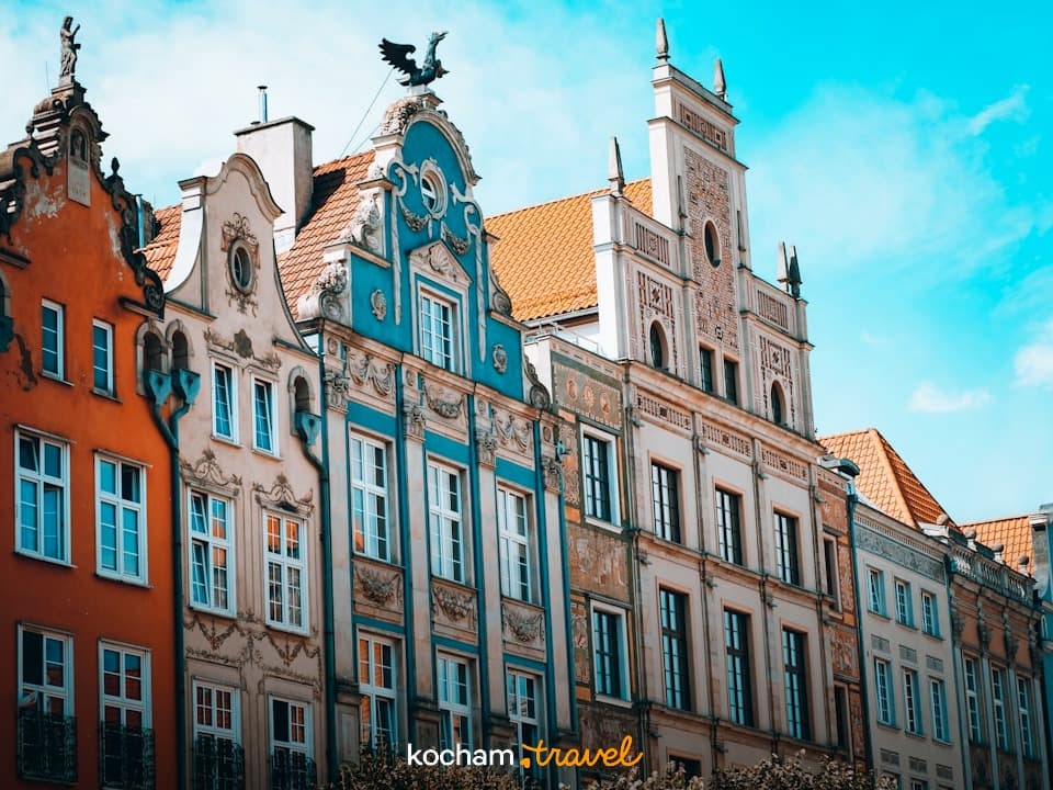 Kolorowe historyczne kamienice z ozdobnymi fasadami pod błękitnym niebem.