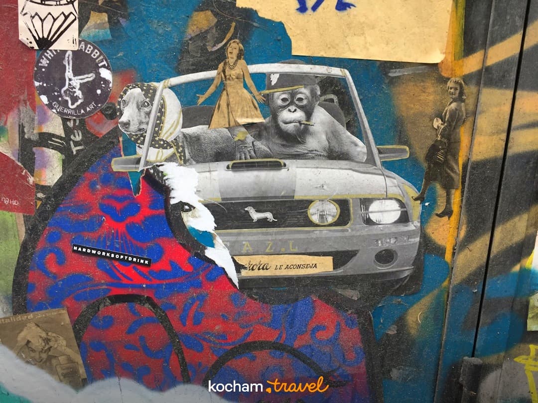 Barwny kolaż street art z orangutanem, psem i samochodem na murze.