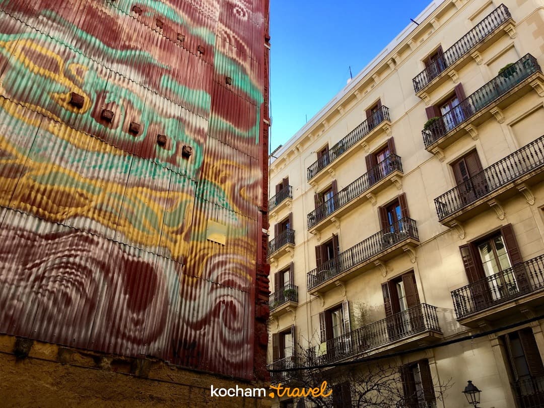 Kolorowe graffiti na ścianie i tradycyjne budynki z balkonami w mieście.