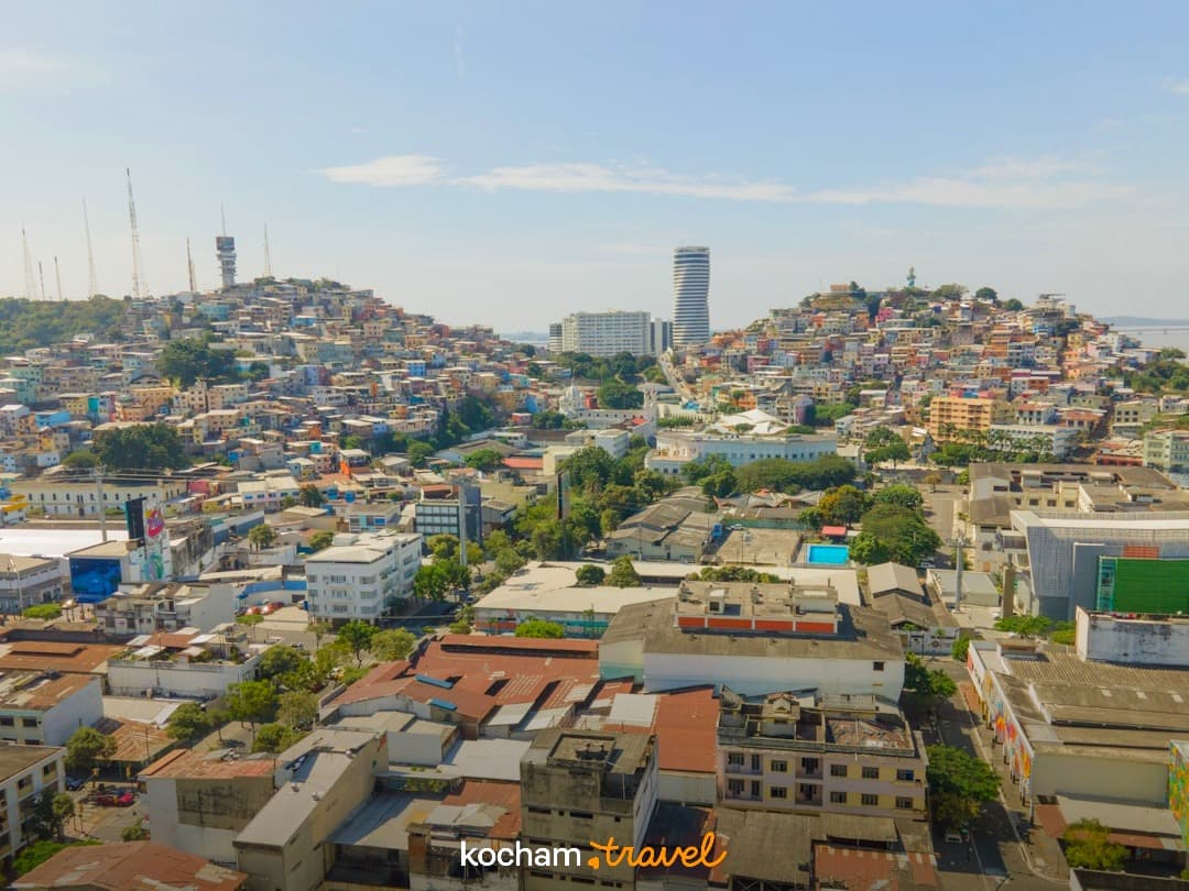 Panoramiczny widok miasta, kolorowe domy na wzgórzach, nowoczesny drapacz chmur.