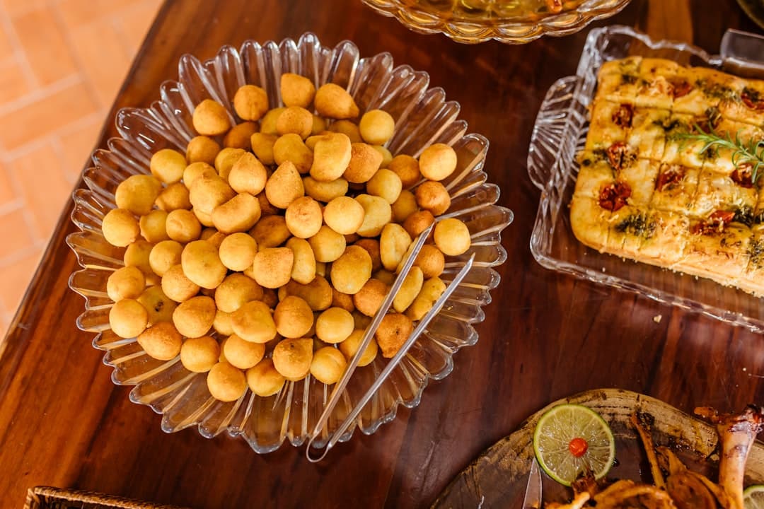 Złociste smażone przekąski, focaccia i pieczone mięso na stole bufetowym.