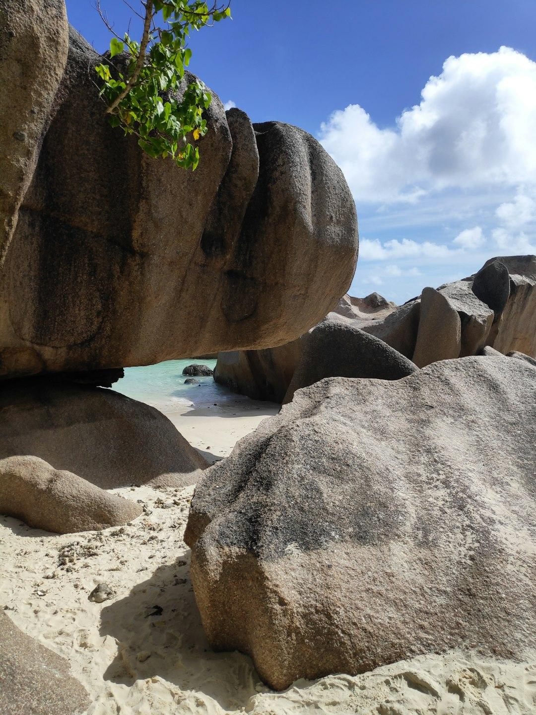 Granitowe głazy na tropikalnej plaży z turkusowym oceanem pod błękitnym niebem.