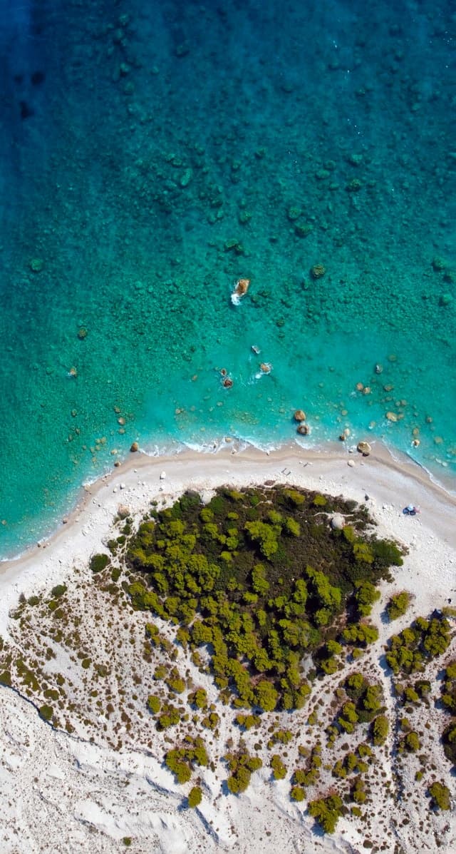 Malownicza plaża z turkusową wodą i zielonym lasem z lotu ptaka.