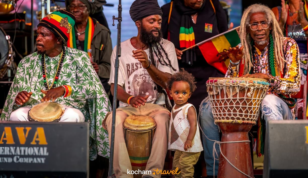 Rastafariańscy muzycy grający na bębnach, z dzieckiem obok.