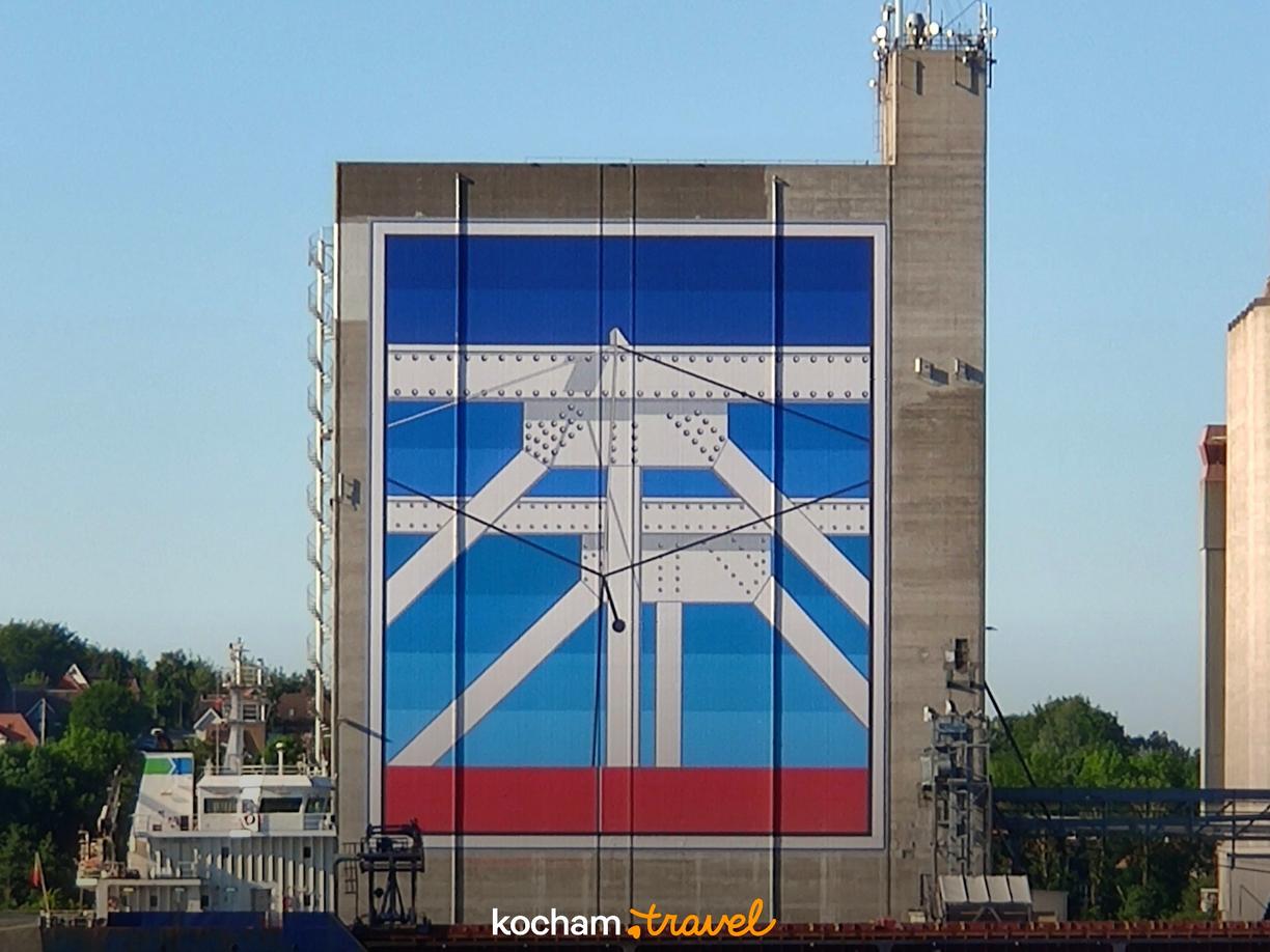 Imponujący mural mostu i zegara na silosie portowym.