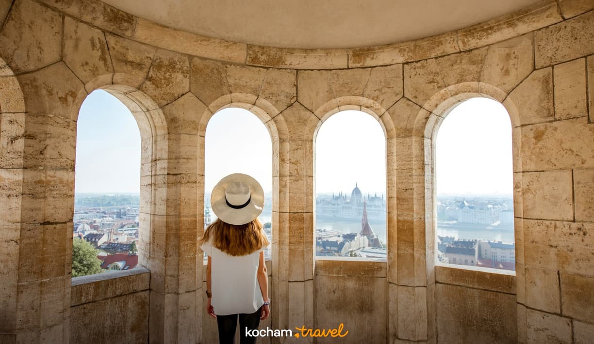 Kobieta w kapeluszu podziwia panoramę Budapesztu z Baszty Rybackiej.