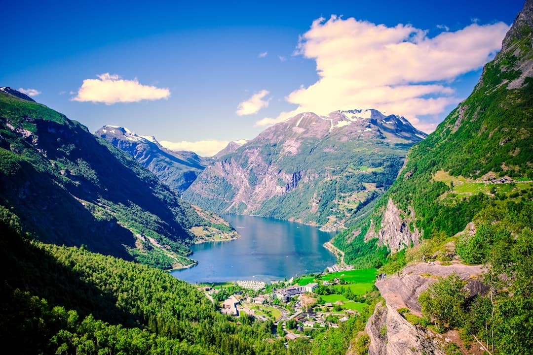 Malowniczy fiord, zielone góry, błękitna woda, wioska w dolinie.