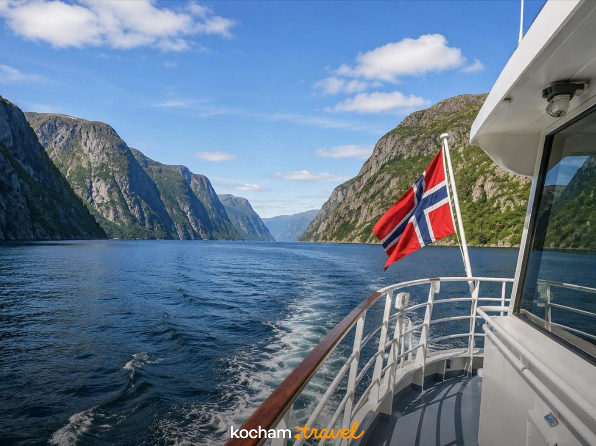 Rejs statkiem po norweskim fiordzie z powiewającą flagą Norwegii.