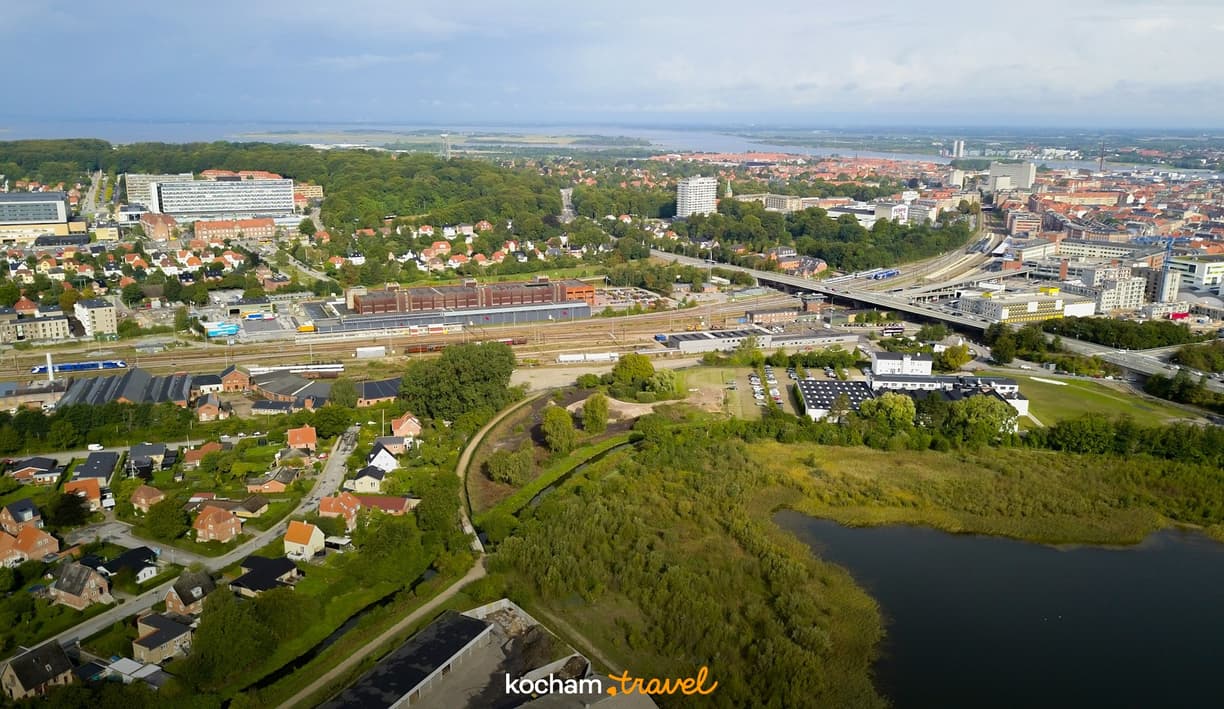 Miasto z lotu ptaka: zabudowania, zieleń, tory kolejowe i jezioro.