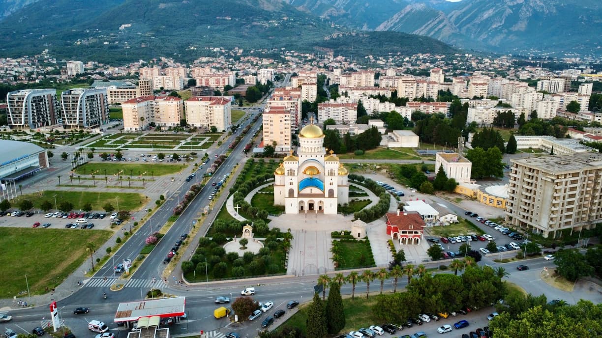 Panorama miejska Podgoricy z imponującą katedrą i górami w tle.