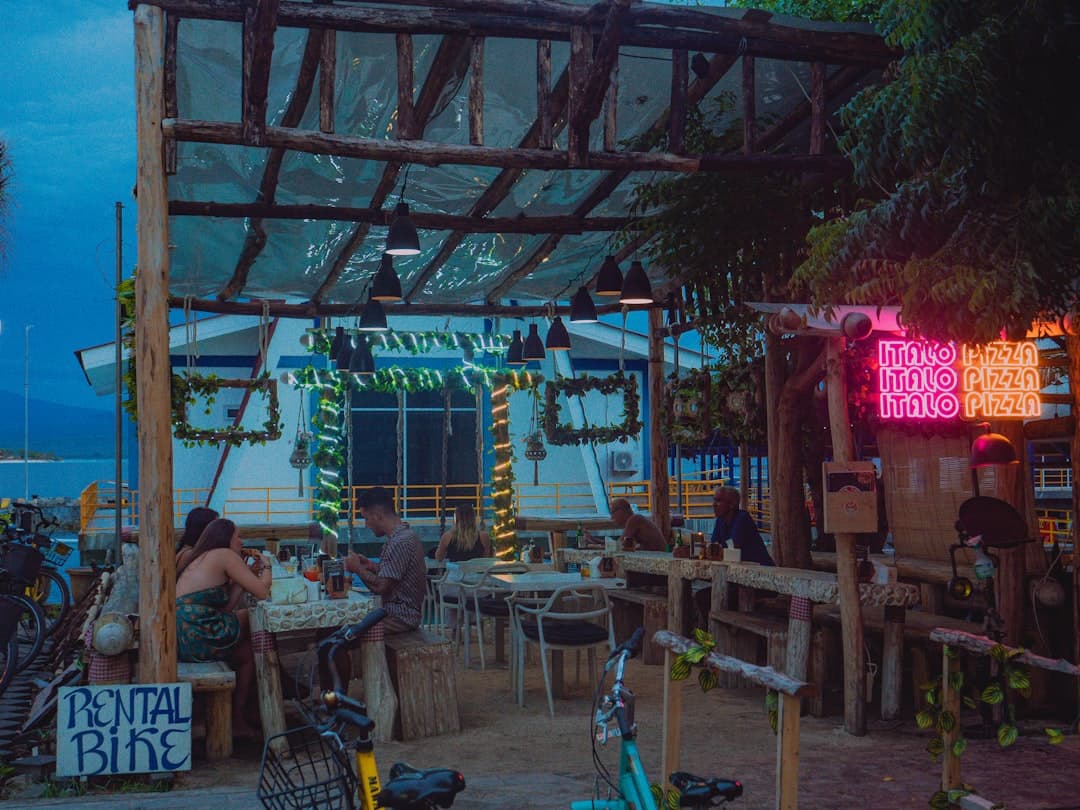 Restauracja na świeżym powietrzu z neonem i rowerami wieczorem nad morzem.