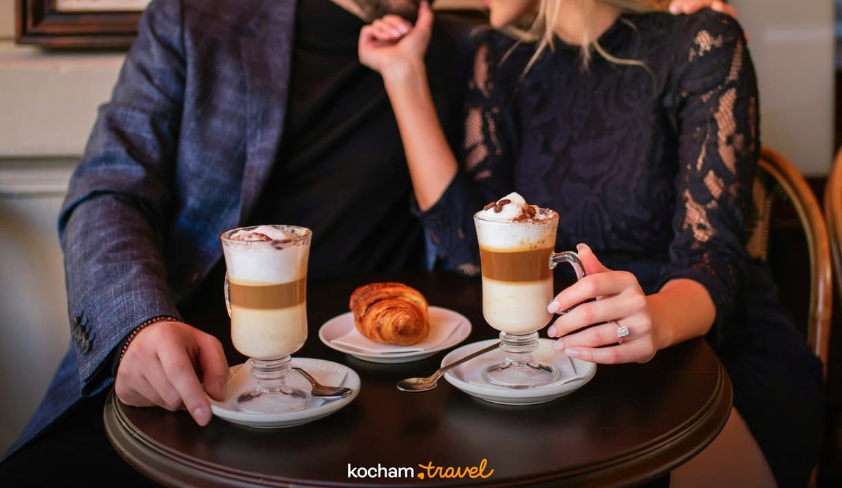 Zakochana para delektuje się kawą i rogalikiem w przytulnej kawiarni.