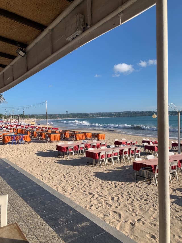 Restauracja na piaszczystej plaży z widokiem na ocean i fale.