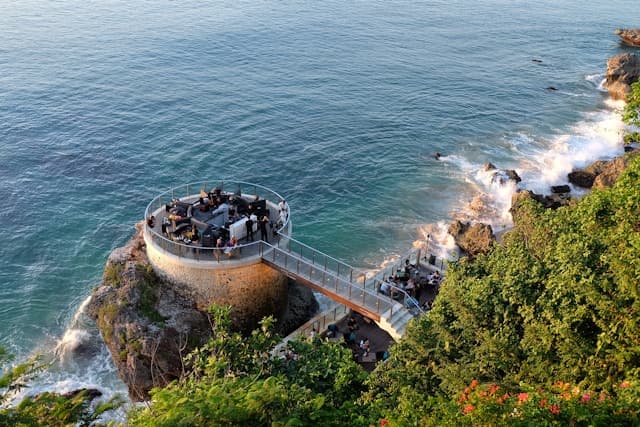 Unikalny bar na klifie z tarasem nad oceanem, otoczony zielenią.