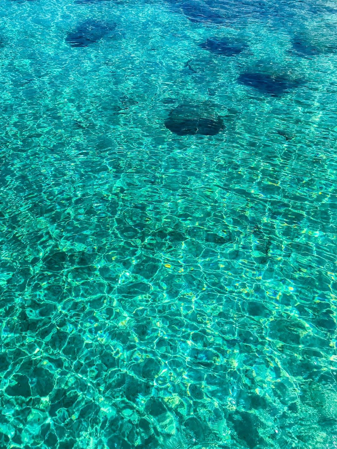 Przejrzysta turkusowa woda oceaniczna z refleksami słońca na powierzchni.