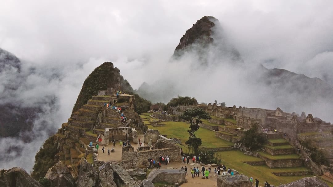 Starożytne ruiny Machu Picchu w Peru we mgle z turystami.