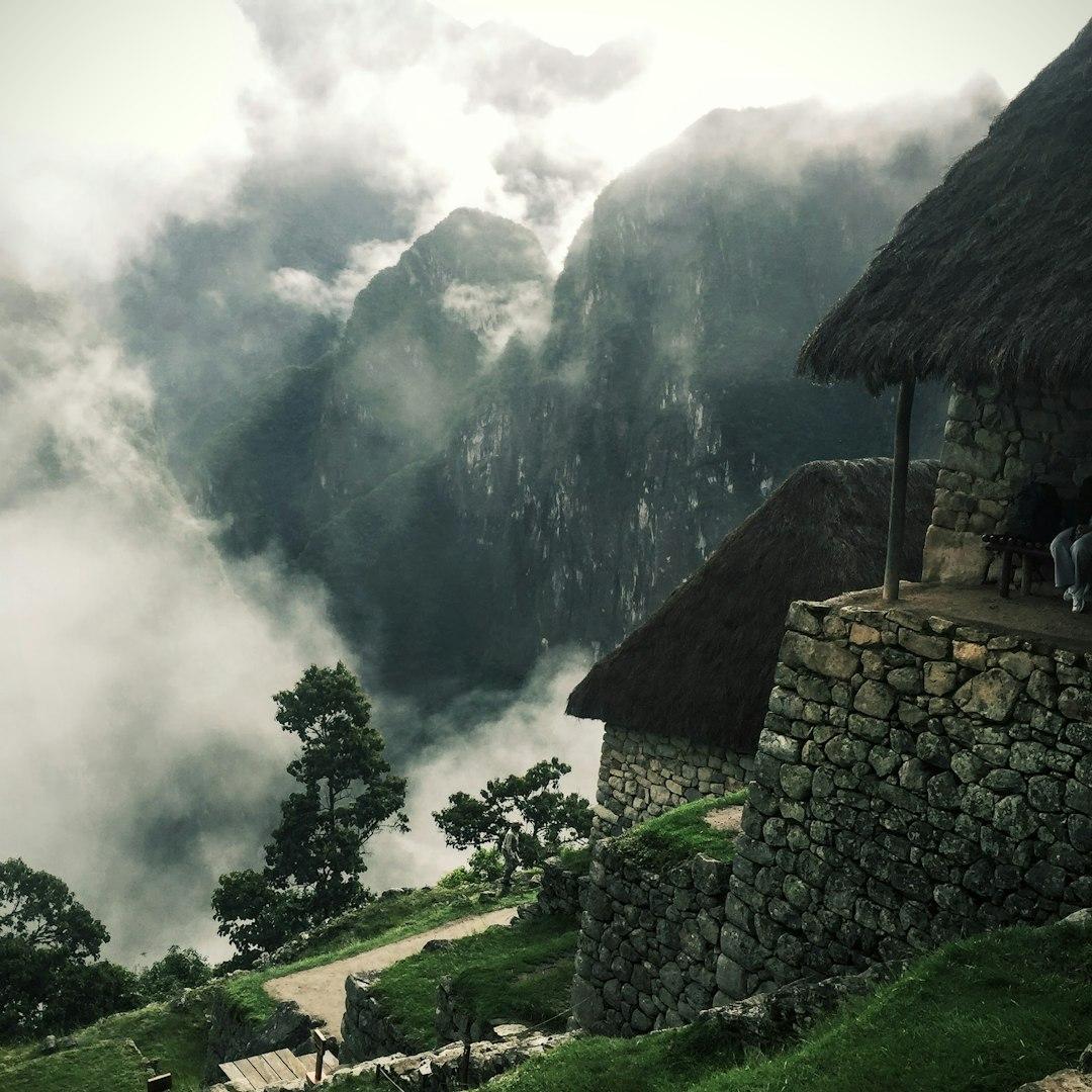 Machu Picchu, mgliste góry, kamienne budynki, dachy kryte strzechą