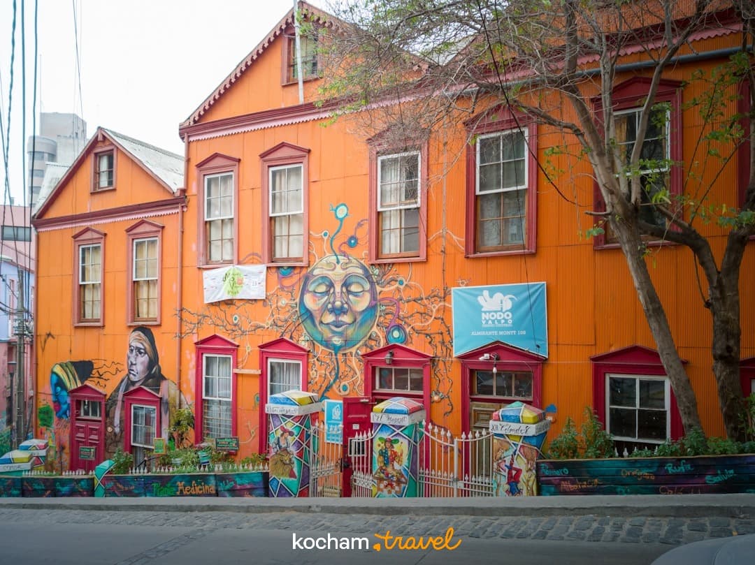 Kolorowy pomarańczowy budynek ze sztuką uliczną Valparaiso.