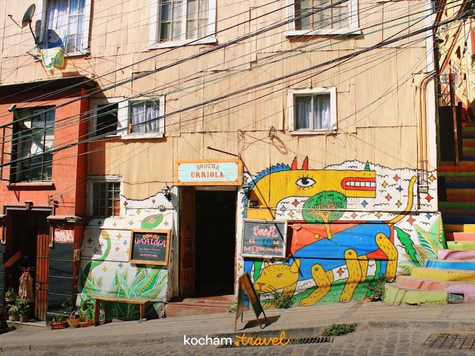 Wibrujący mural na budynku, kolorowe schody, słoneczna scena miejska.