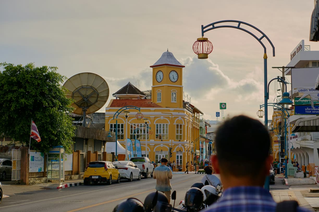 Uliczna scena w Starym Mieście Phuket z żółtym budynkiem z wieżą zegarową.